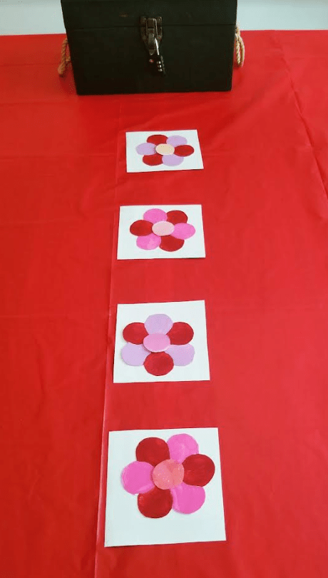 diy valentines day escape room shows four colorful hearts on a table with white square behind each.
