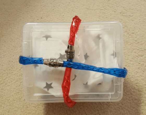 diy escape room lock box ideas shows a locked clear box with two bike locks locking the lid to the bottom.