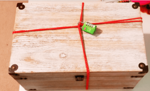 diy escape room lock box ideas shows a large box with string around and across it and locked in the center.