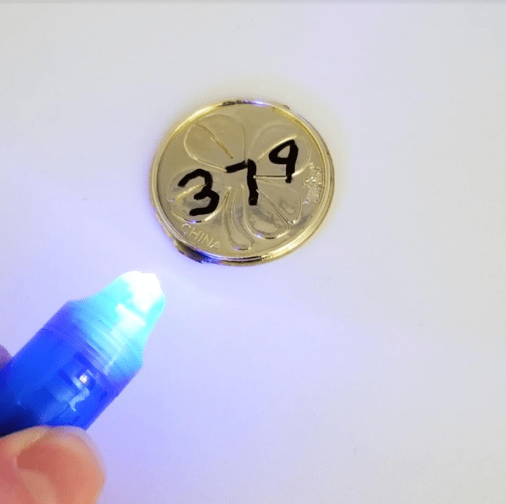 st. patrick's day escape room shows a uv light being shon onto a coin.
