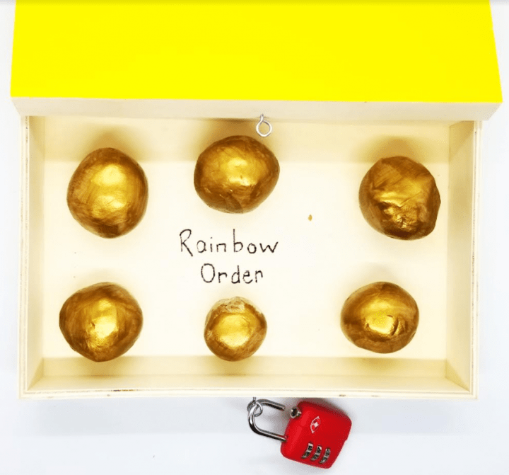 st. patrick's day escape room shows six balls of shiny gold clay in a box.