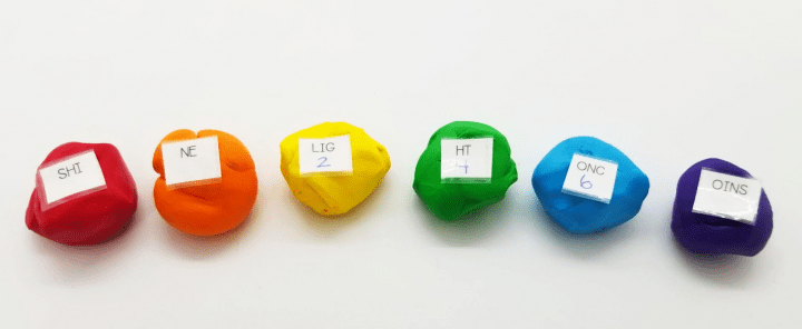 st. patrick's day escape room shows rainbow colored balls of dough with paper square with letters in each.