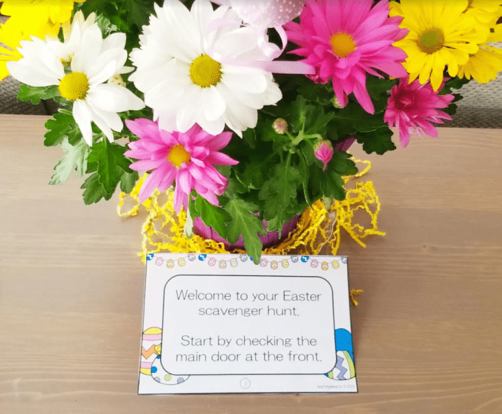 Free Easter scavenger hunt shows flowers and a note clue in front of it.