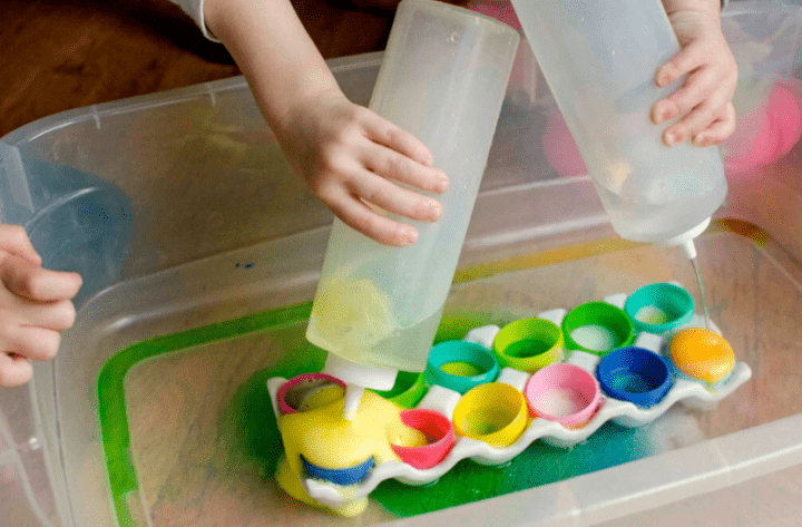 Easter stem for kids shows children pouring bottles onto plastic eggs that are fizzing.