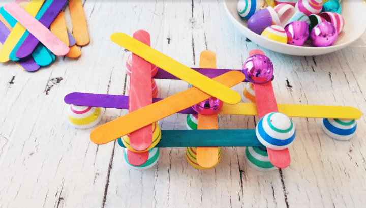 Easter STEM activity shows plastic Easter eggs and popsicle sticks and a structure.