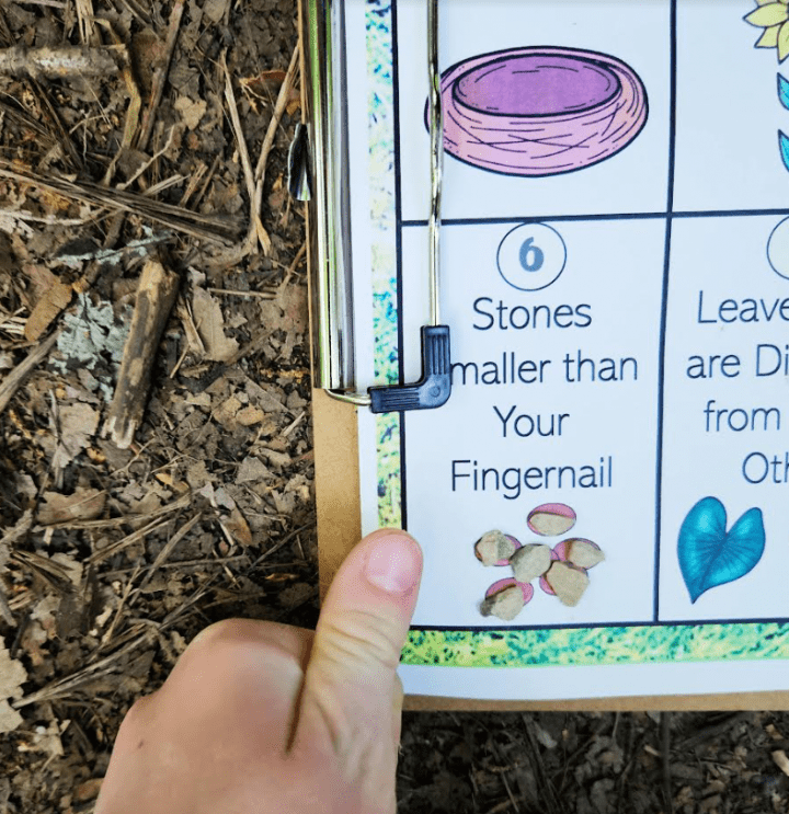 free printable scavenger hunt shows a printable page and stones set on it and a child's thumb.