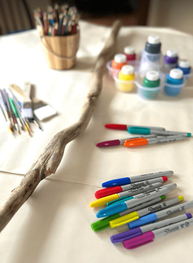 nature art shows a wooden stick, markers and paints and art supplies.