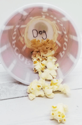 birthday escape room for kids shows a popcorn container with popcorn pieces and the word dog written in the bottom.