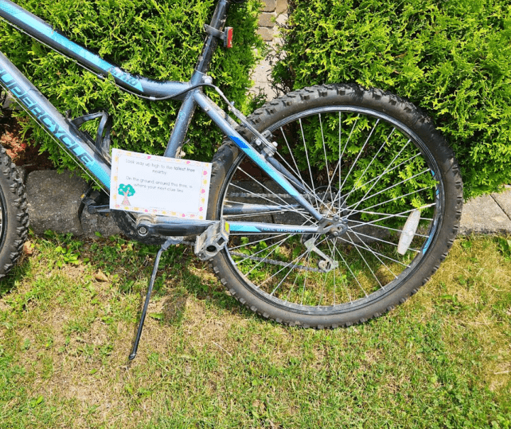 summer scavenger hunt shows a bike with a printed scavenger hunt clue stuck to it.