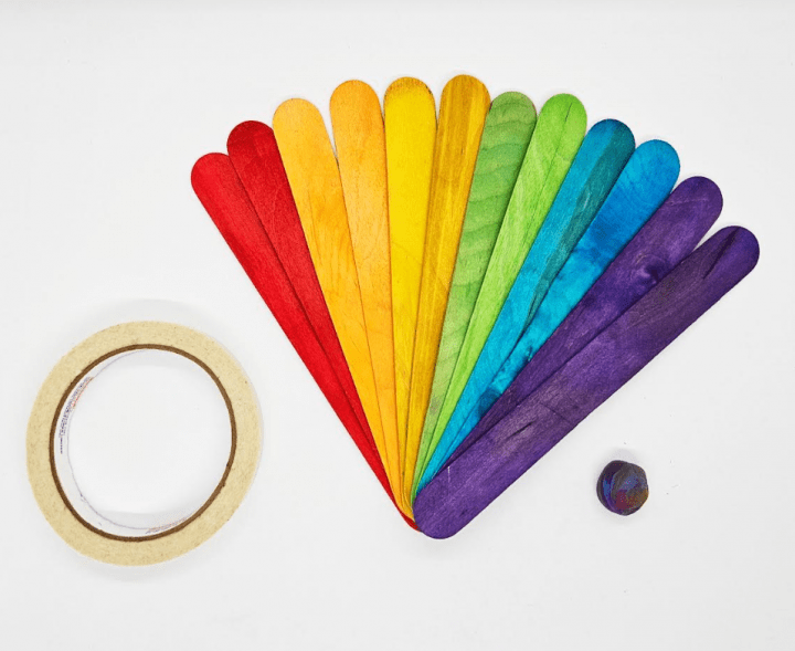 popsicle stick STEM activity shows a roll of tape, rainbow of jumbo popsicle sicks and a ball of playdough.