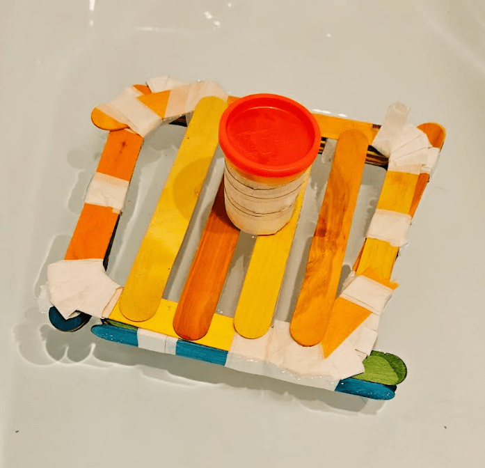 build a boat shows a square popsicle sticks and a layer of sticks on top and a container of play dough.