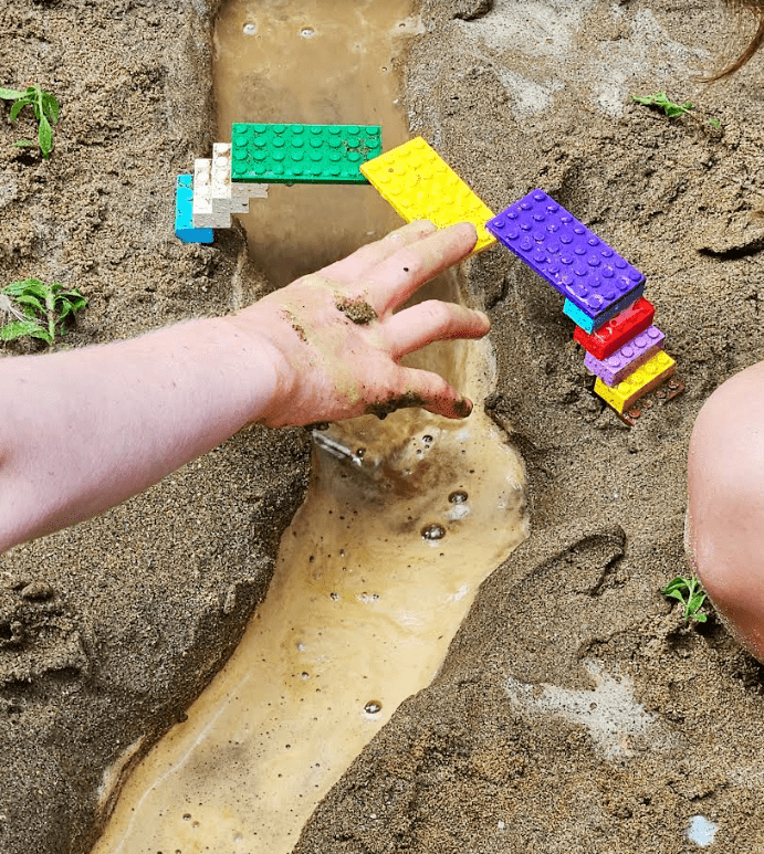 bridge building shows a child making a bridge in the sand with a stream flowing under it.