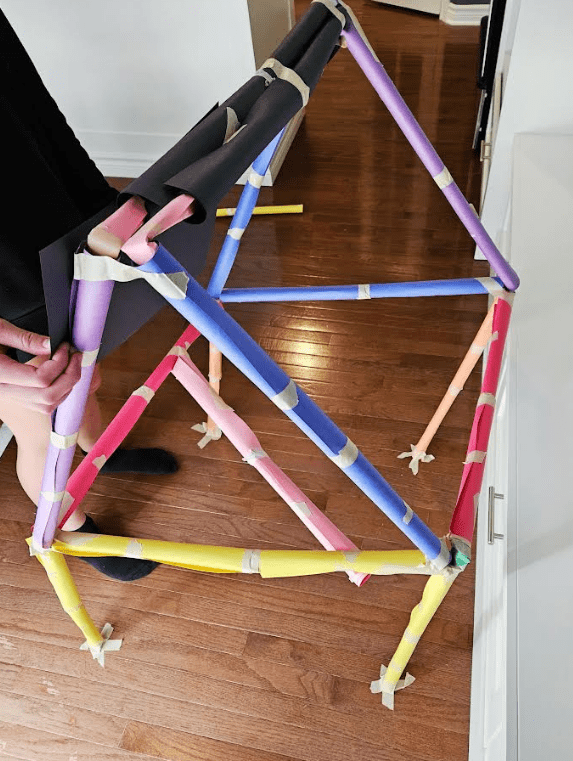 easy stem activity shows a child creating a colorful construction paper house.