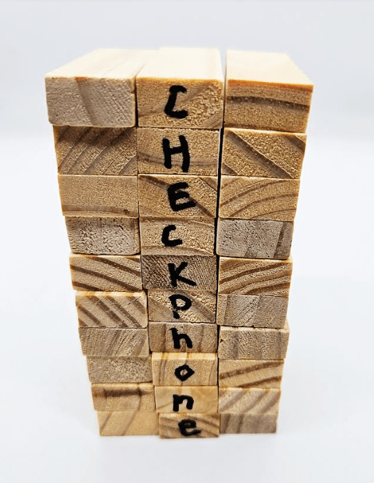 DIY escape room shows a tower of wooden blocks with the words checkphone down the middle blocks.