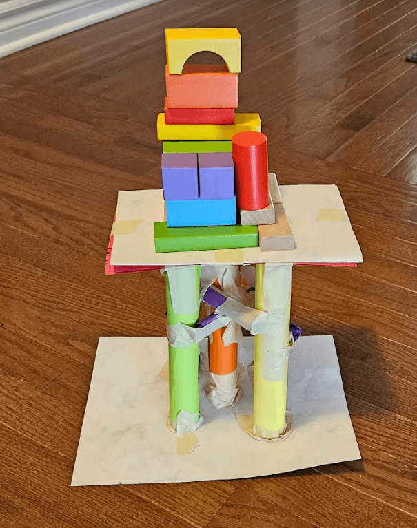 paper STEM activity shows a tower with wooden blocks on top of a paper tower.