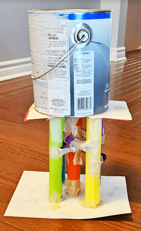 building challenge shows a paper structure with a paint can on top.
