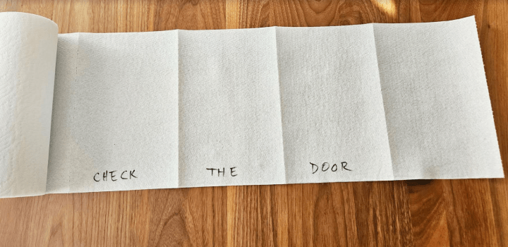 diy escape room game shows a roll of paper towel unrolled with the words check the door printed on the bottom.