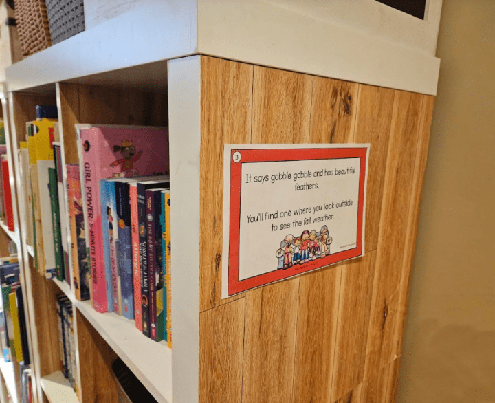 free scavenger hunt shows a printed scavenger hunt clue on the side of a bookcase.