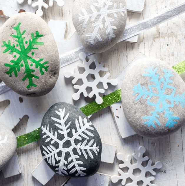 winter craft ideas shows rocks painted with snowflakes on them.