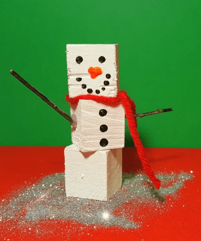 preschool christmas crafts shows a snowman craft made from wood cubes.