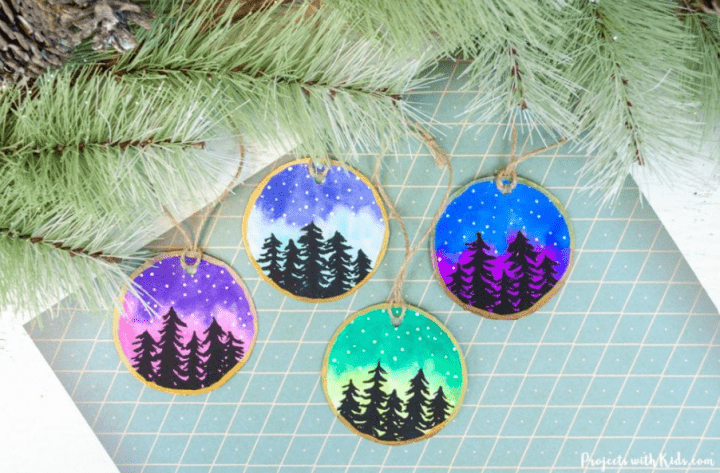 preschool christmas craft shows wood slice ornaments with the Northern lights painted on.