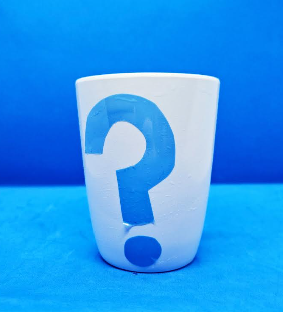 puzzle game shows a white mug with a blue question mark sticker on it.