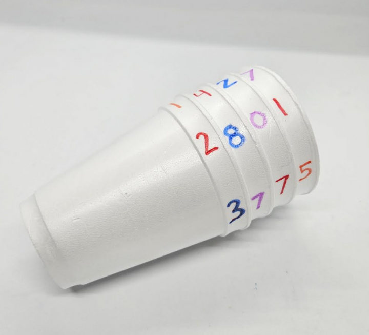 diy escape room for kids shows a stack of cups with numbers around the edge of each.