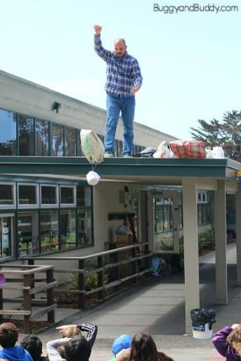 egg drop STEM challenge shows a man standing on a roof dropping an egg drop container.