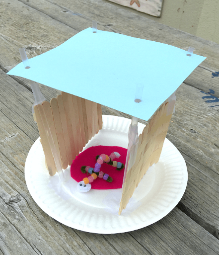 STEM activity for kids shows a home made from popsicle sticks and a bead critter inside.