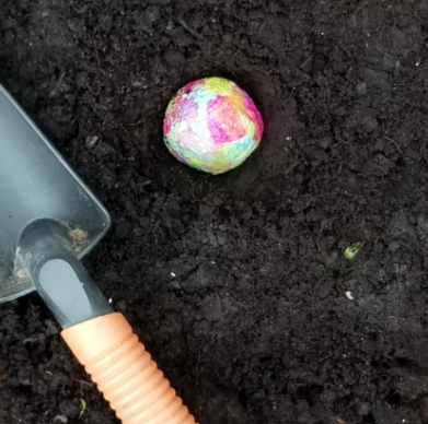 recycled crafts for kids shows a seed ball buried in the soil.
