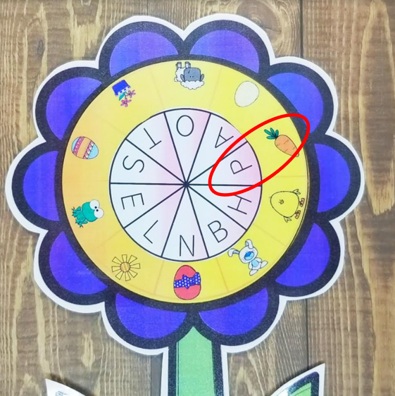 spring escape room shows a flower with pictures around the center and a letter code on top.  The letter P and the carrot are lined up and circled.