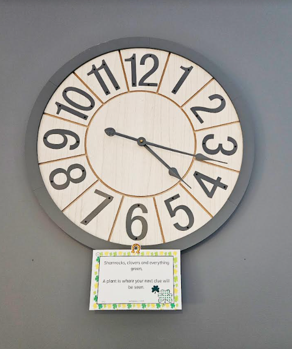 st patricks day scavenger hunt shows a clock on a the wall with a riddle taped to the bottom.