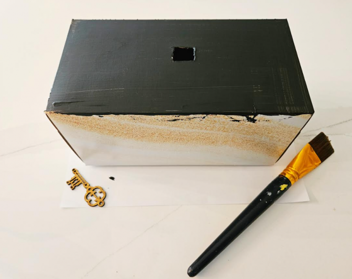 puzzle game for kids shows a kleenex box painted black with a small square cut in the top.