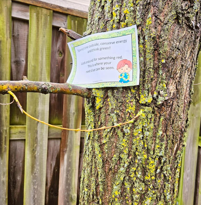 scavenger hunt for kids shows a printable riddle on a tree.