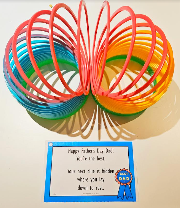 free treasure hunt shows a large slinky in front of a printable riddle.