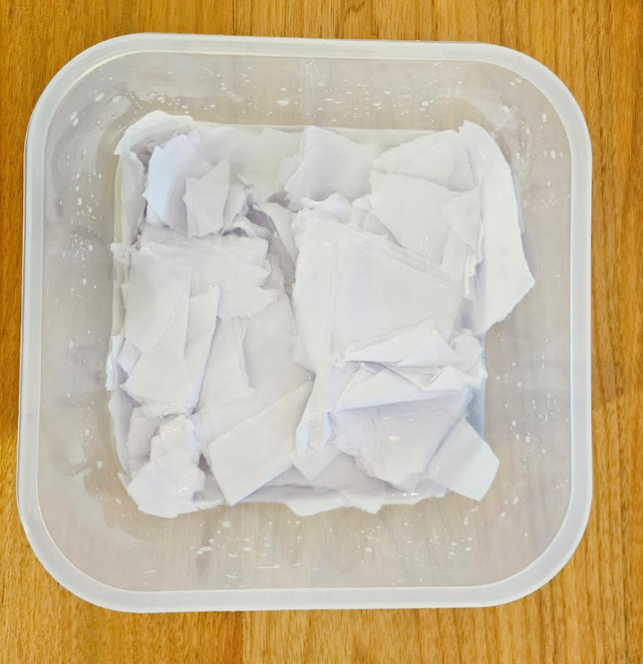 art project for kids shows a container with paper soaking in water.