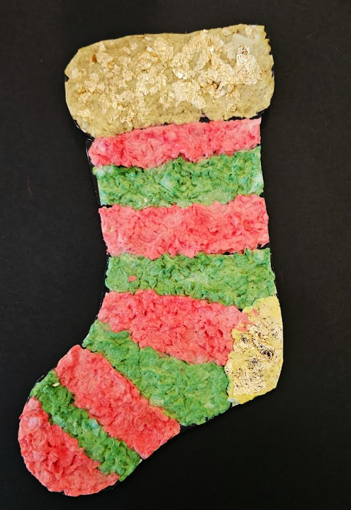 christmas stocking paper mache shows a stocking image filled in with paper mache with a black background.