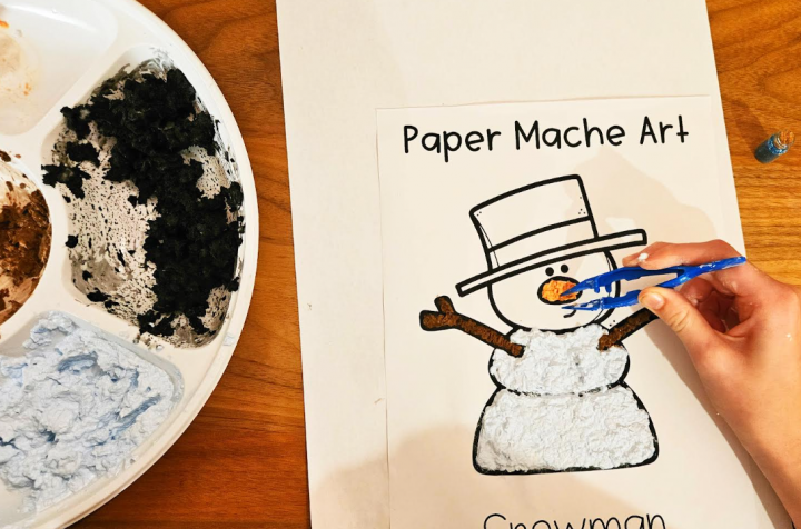 paper mache art shows a child making paper mache and filling in a snowman image with the pulp.