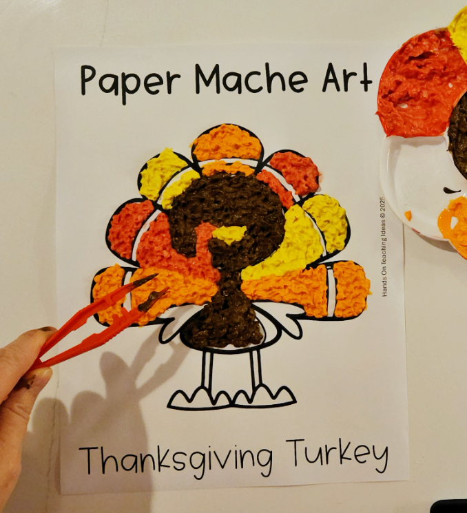 Thanksgiving paper mache art shows a child using tweezers to fill in sections of the turkey with paper mache.