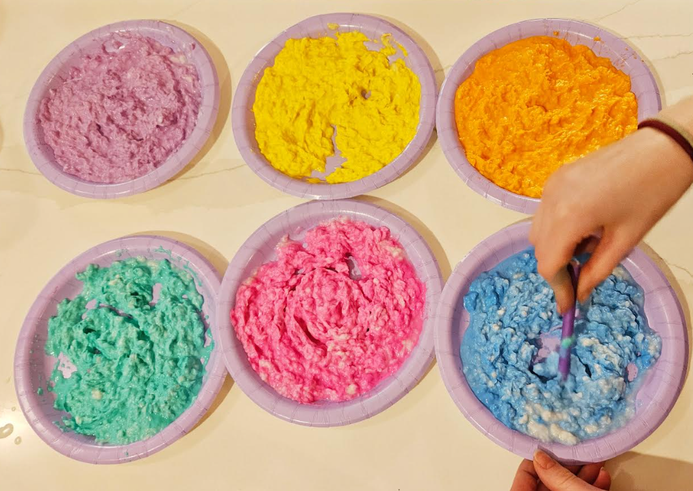 how to make paper mache shows a child mixing paint into a paper mache mixture.
