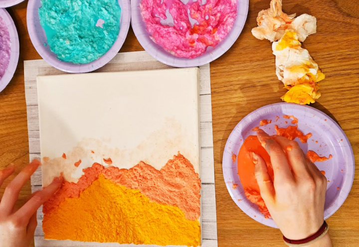 paper mache art shows a child adding orange paper mache pulp to create what looks like a mountain.