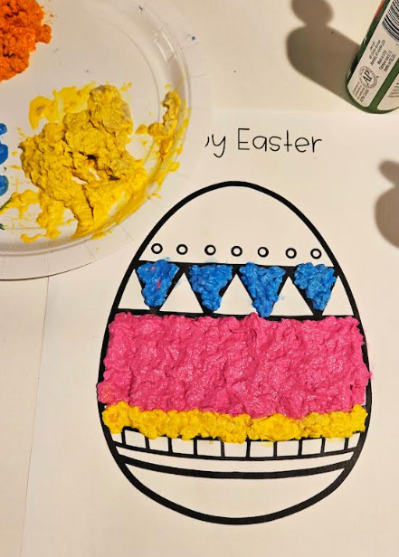 Easter craft for kids shows an egg template with some sections filled with colorful paper mache.