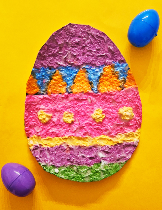 Easter art shows a cut out of an Easter egg with two plastic eggs to the side.