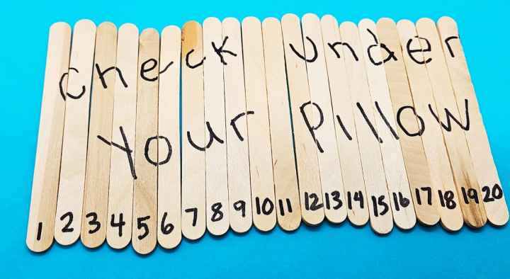 escape room themes shows a puzzle made from a bunch of popsicle sticks that has the words check under your pillow written across.