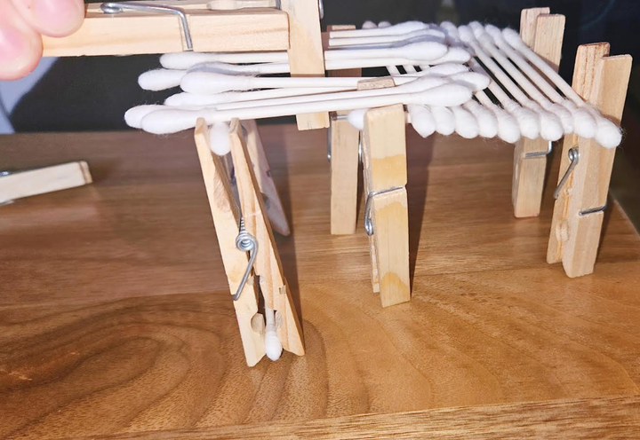 building challenge shows a child connecting clothes pins.