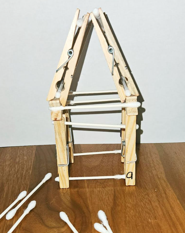 building activity for kids shows a house made from cotton swabs and clothes pins.